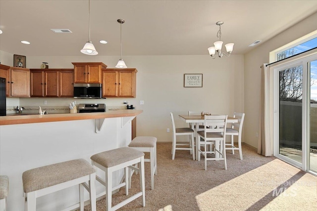 kitchen with visible vents, light countertops, appliances with stainless steel finishes, pendant lighting, and brown cabinets