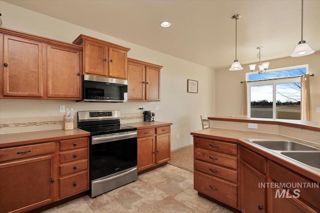 kitchen featuring decorative light fixtures, backsplash, appliances with stainless steel finishes, brown cabinetry, and light countertops