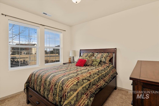 bedroom with baseboards, visible vents, and light carpet