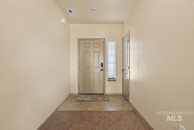 entryway featuring light tile patterned flooring, visible vents, light colored carpet, and baseboards