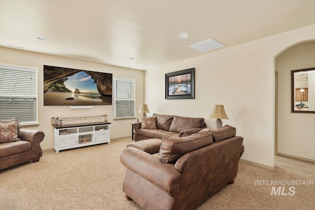 living room with arched walkways, carpet flooring, and plenty of natural light