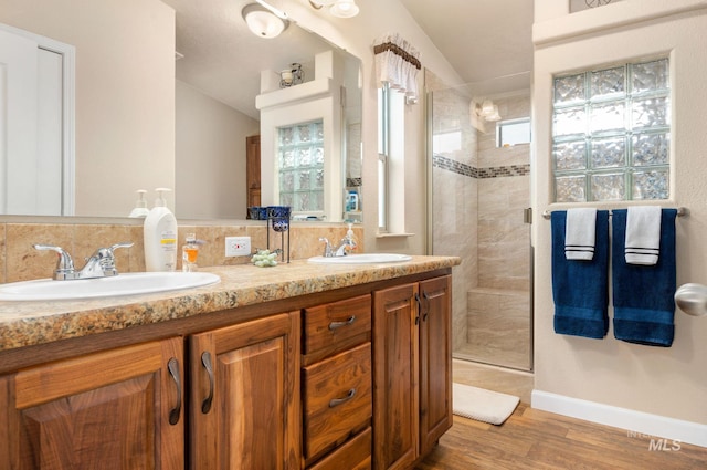 bathroom featuring a sink, baseboards, wood finished floors, and a stall shower