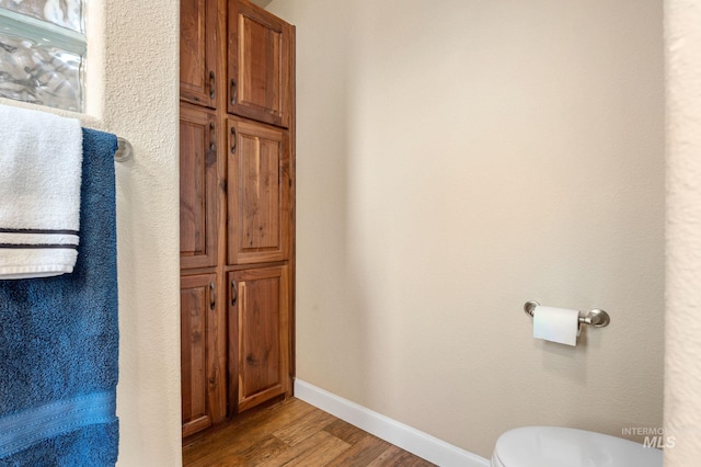 bathroom featuring toilet, baseboards, and wood finished floors