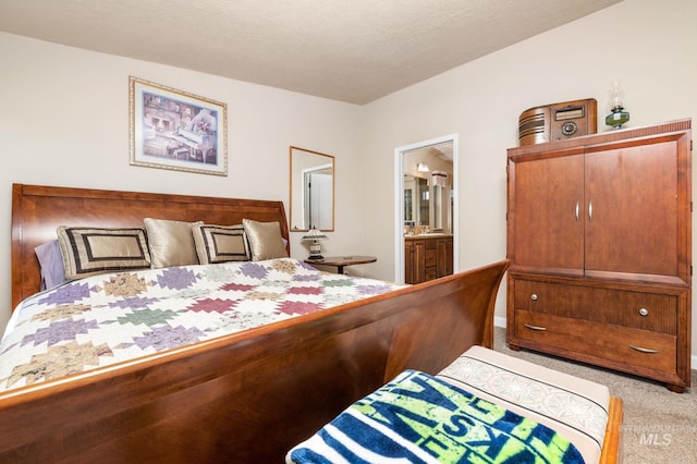 bedroom with light carpet, a textured ceiling, and ensuite bath