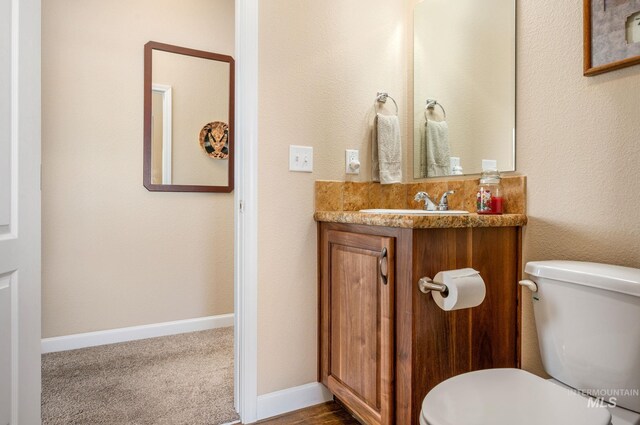 bathroom with toilet, vanity, and baseboards