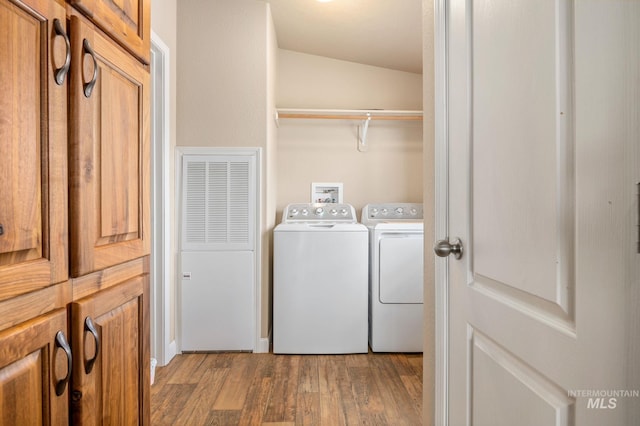 clothes washing area with laundry area, wood finished floors, and washing machine and clothes dryer