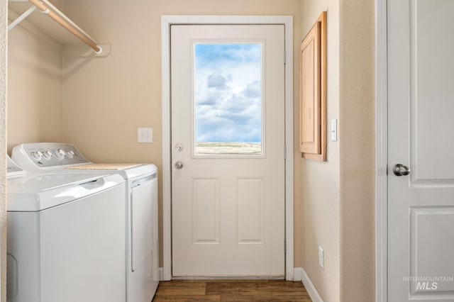 clothes washing area featuring laundry area, wood finished floors, a healthy amount of sunlight, and washing machine and clothes dryer