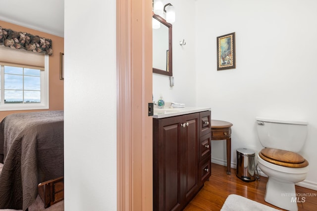 bathroom featuring toilet, ensuite bath, wood finished floors, and vanity