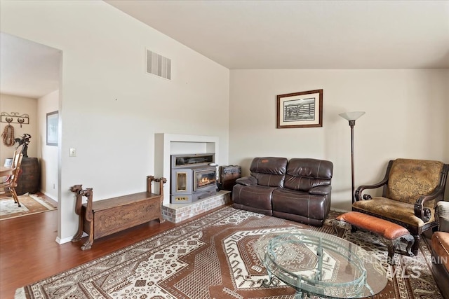 living room with a glass covered fireplace, visible vents, lofted ceiling, and wood finished floors