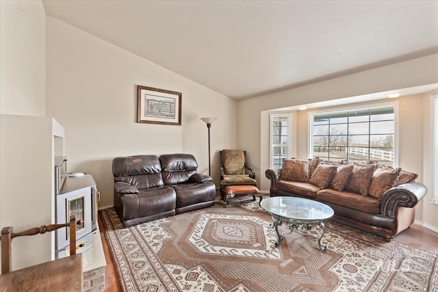 living area featuring vaulted ceiling, wood finished floors, and baseboards