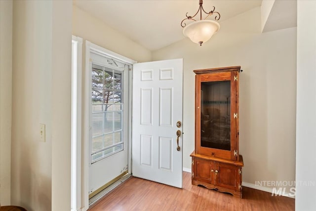 foyer with light wood-type flooring, baseboards, and vaulted ceiling