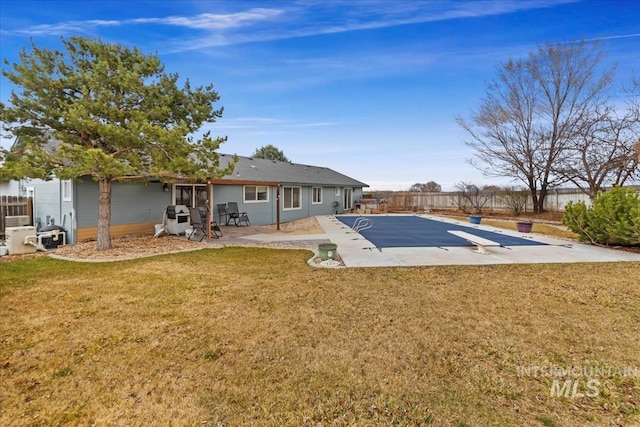 rear view of property featuring a lawn, a fenced backyard, and a patio area