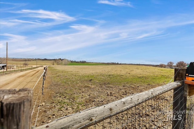 view of yard featuring a rural view, fence, and driveway