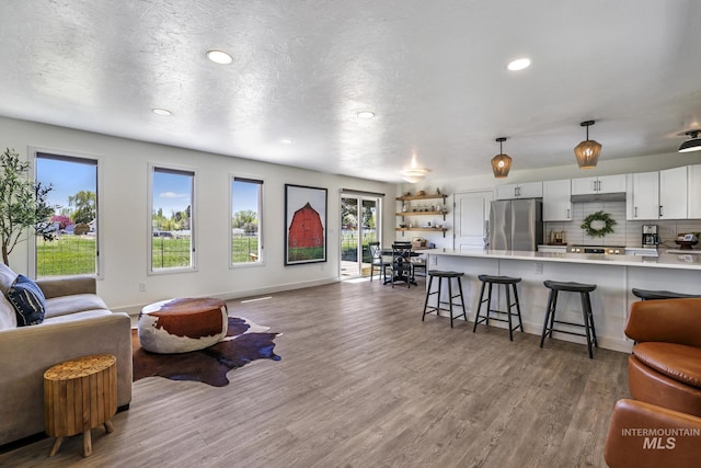 living room featuring recessed lighting, a textured ceiling, baseboards, and wood finished floors