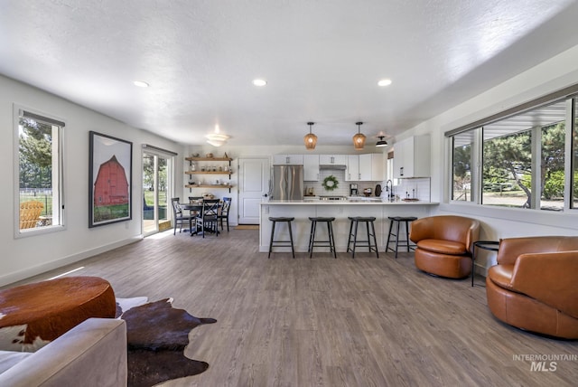 living room featuring baseboards, recessed lighting, and wood finished floors