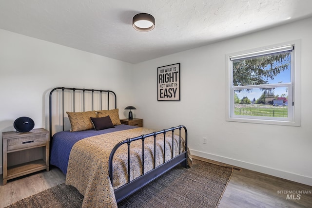 bedroom featuring baseboards, visible vents, and wood finished floors