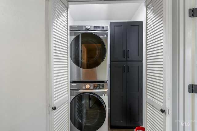 washroom with stacked washer and clothes dryer and cabinet space