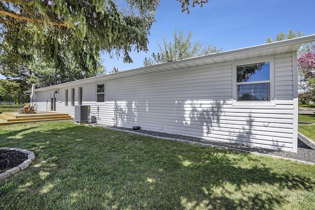 back of house with central AC unit, a wooden deck, and a lawn