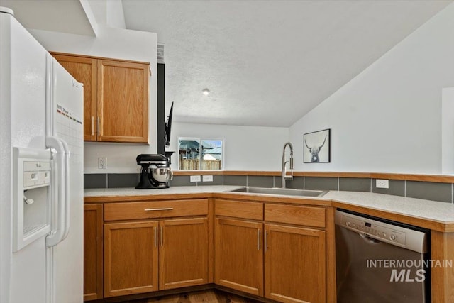 kitchen featuring light countertops, vaulted ceiling, white refrigerator with ice dispenser, stainless steel dishwasher, and a sink