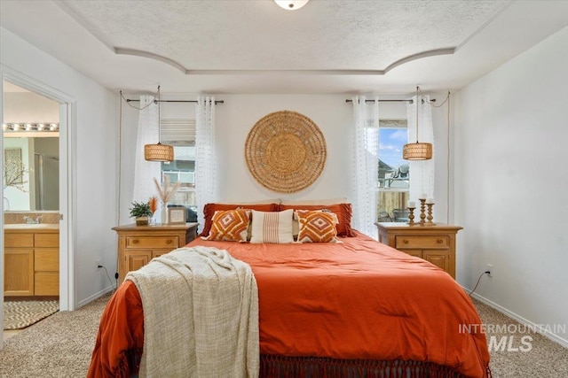 carpeted bedroom featuring connected bathroom, a textured ceiling, and baseboards