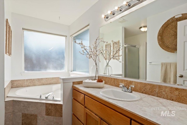 bathroom with vanity, a shower stall, a garden tub, and visible vents