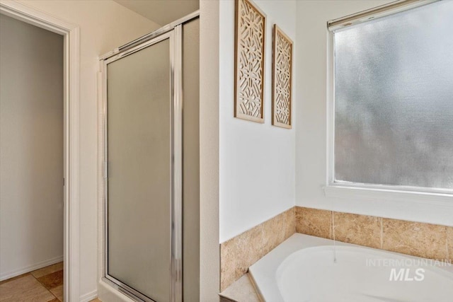 full bath featuring plenty of natural light, a shower stall, and a garden tub