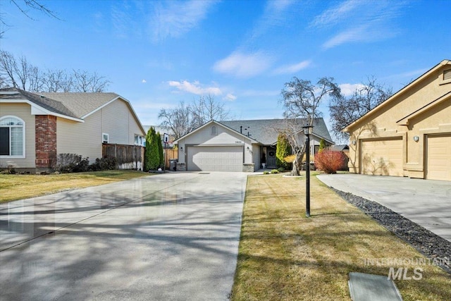 view of front facade with driveway, an attached garage, a front yard, and fence