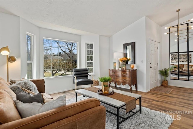 living room featuring baseboards, a textured ceiling, lofted ceiling, and wood finished floors