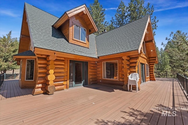 rear view of property featuring a shingled roof, a deck, and log siding