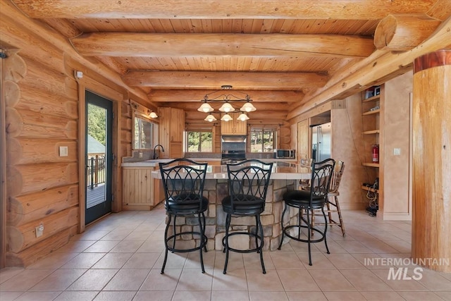 kitchen featuring a sink, a breakfast bar area, light countertops, wooden ceiling, and light tile patterned floors