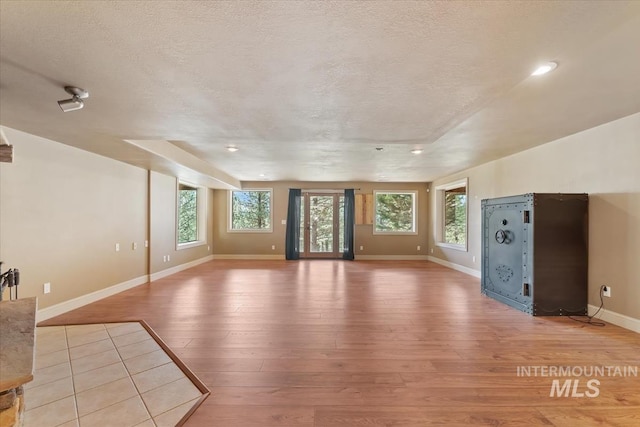unfurnished living room with recessed lighting, baseboards, light wood-type flooring, and a textured ceiling