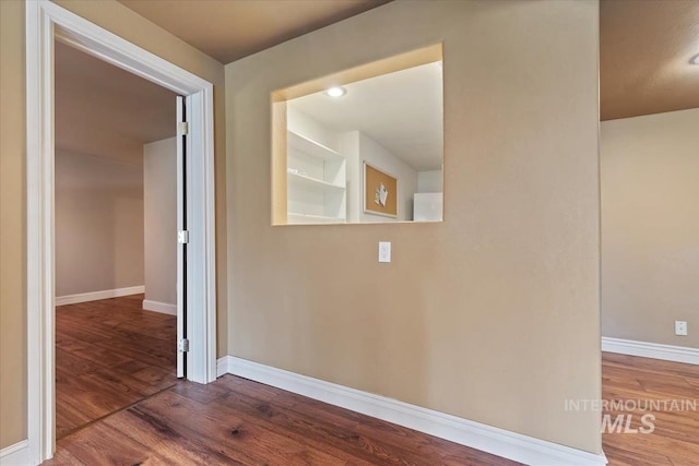 corridor featuring baseboards and wood finished floors