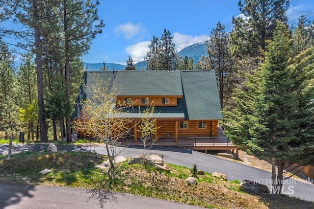 cabin featuring covered porch, driveway, a chimney, log siding, and a mountain view