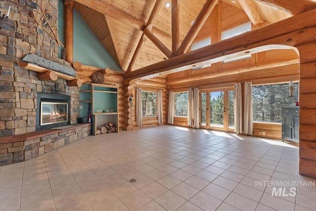 unfurnished living room with beamed ceiling, a stone fireplace, high vaulted ceiling, wood ceiling, and tile patterned floors