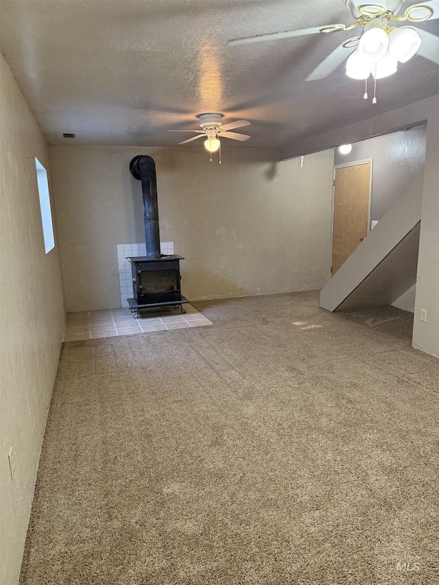 140 Quick Silver Ave, Hagerman, ID 83332 - unfurnished living room with a ceiling fan, a wood stove, stairs, a textured ceiling, and carpet