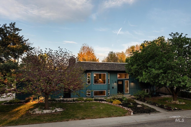 view of front of property featuring a front yard, a chimney, and a shingled roof