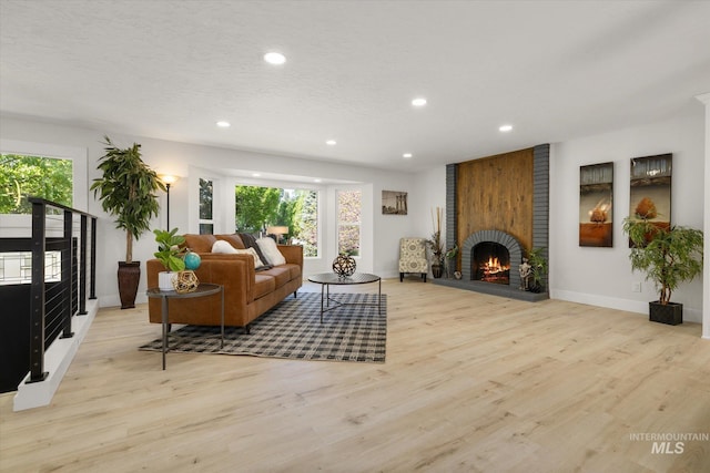 living room featuring a brick fireplace, recessed lighting, light wood-style floors, and baseboards