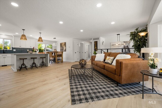 living room featuring light wood-type flooring, recessed lighting, and baseboards