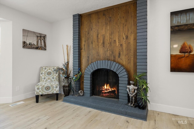 sitting room featuring baseboards, wood finished floors, and a fireplace