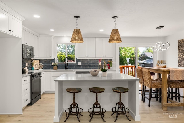 kitchen featuring black / electric stove, a sink, stainless steel microwave, plenty of natural light, and recessed lighting