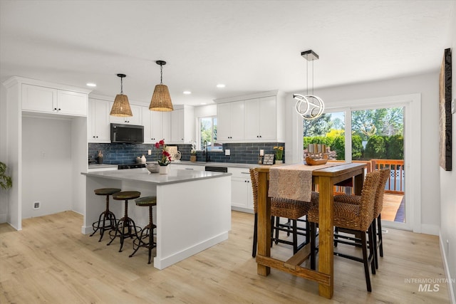 kitchen featuring backsplash, white cabinetry, light wood-type flooring, a kitchen island, and recessed lighting