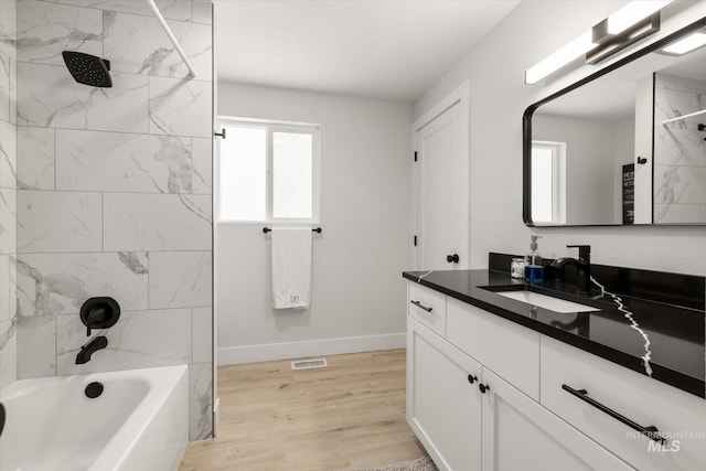 full bathroom featuring baseboards, wood finished floors, shower / washtub combination, and vanity
