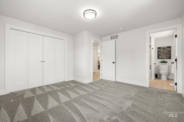 unfurnished bedroom featuring carpet flooring, baseboards, a closet, and connected bathroom