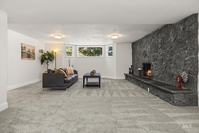carpeted living area featuring a textured ceiling, a stone fireplace, and baseboards