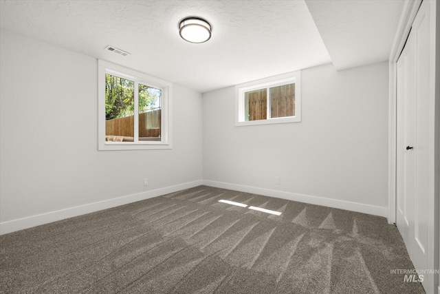 unfurnished bedroom featuring dark carpet, baseboards, a closet, and a textured ceiling