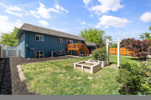 back of property with a gate, a garden, central AC unit, stairs, and a wooden deck