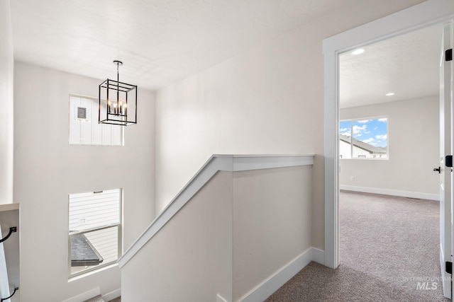 stairway with carpet flooring, an inviting chandelier, and baseboards