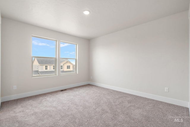 carpeted empty room with visible vents and baseboards