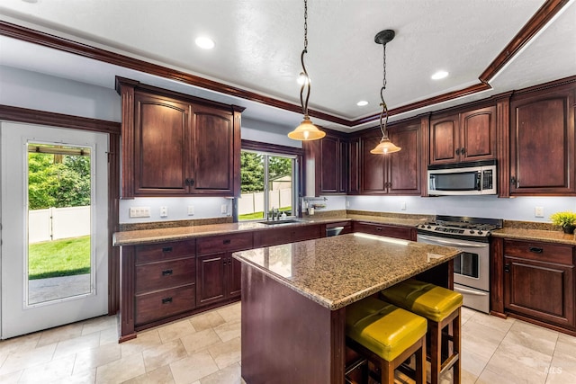 kitchen featuring a center island, a breakfast bar area, dark stone counters, appliances with stainless steel finishes, and a sink