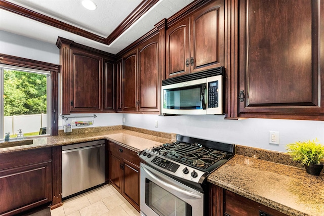 kitchen featuring ornamental molding, a sink, dark stone countertops, stainless steel appliances, and light tile patterned floors